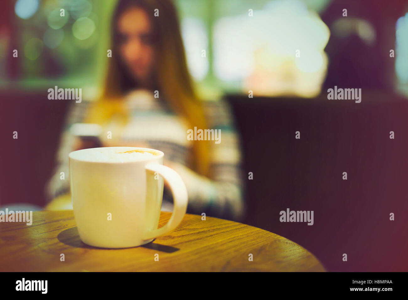 Tazza di caffè nella caffetteria e la donna con il telefono cellulare. In stile vintage effetto immagine Foto Stock