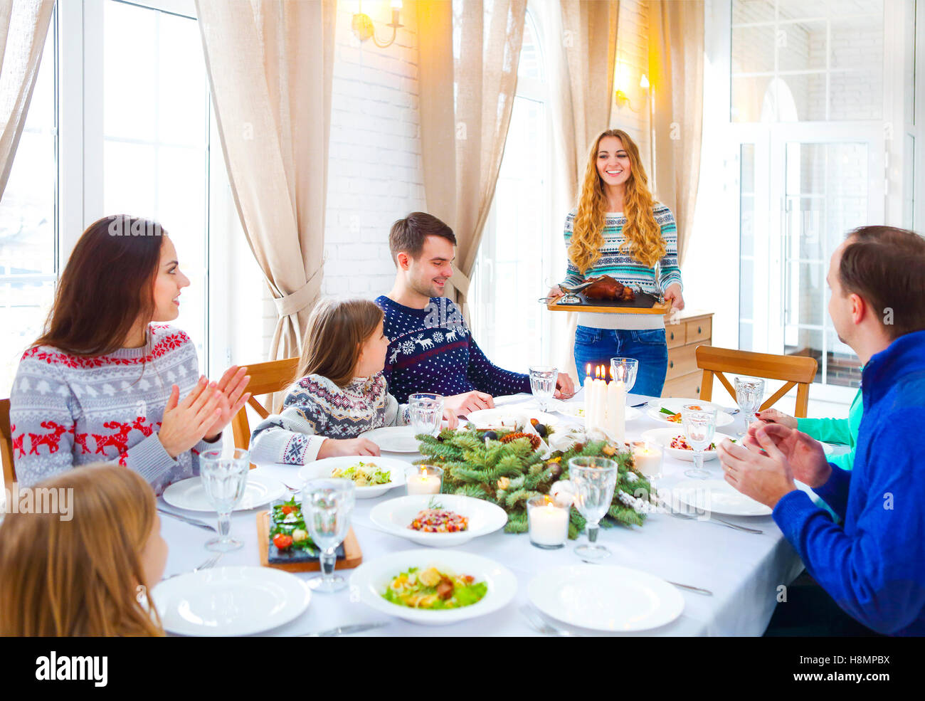 Happy amici seduti attorno a un tavolo e godersi la cena di Natale insieme Foto Stock