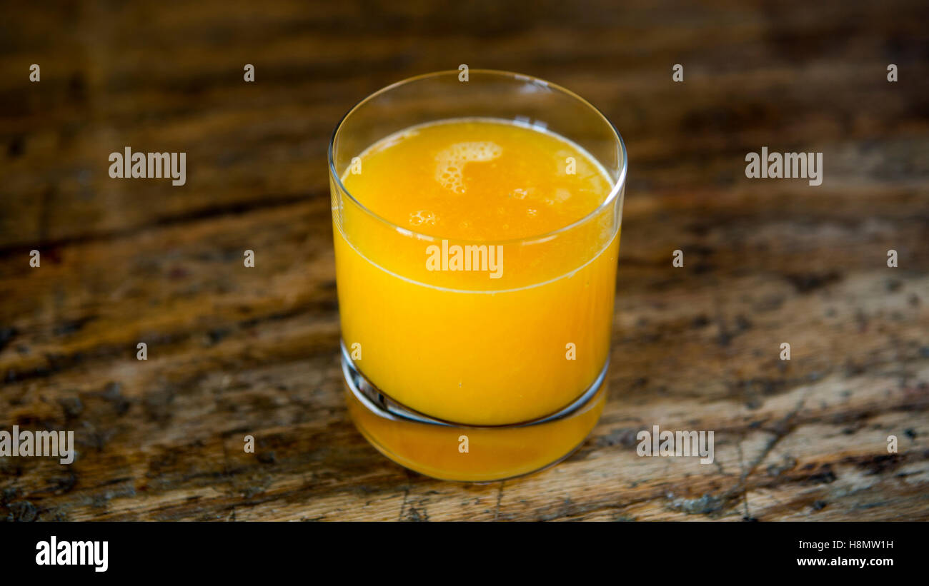 Bicchiere di succo d'arancia appena spremuto su una tavola in legno rustico Foto Stock