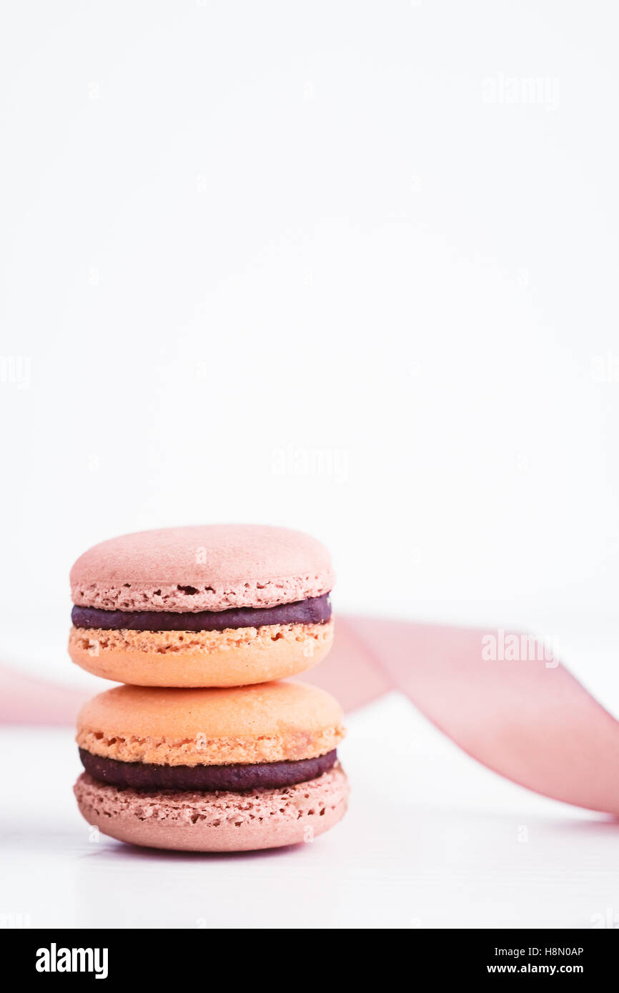 French macarons con glassa al cioccolato in colori pastello. Sfondo bianco Foto Stock