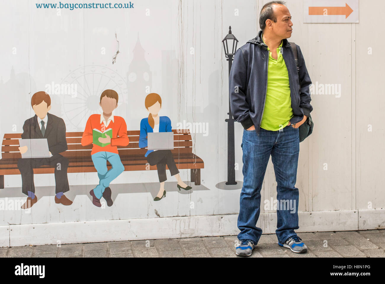 Un uomo in piedi di fronte ad una freccia che punta nella direzione che egli sta cercando. Per il suo lato destro è un disegno di tre persone su una panchina nel parco. Foto Stock