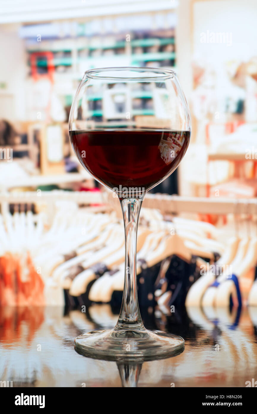 Bicchiere da vino contro vestiti sfocata sullo sfondo del negozio Foto Stock