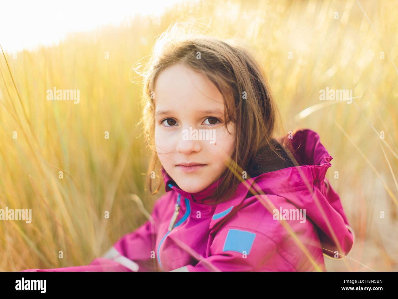Ritratto di ragazza (10-11) seduto in erba alta Foto Stock