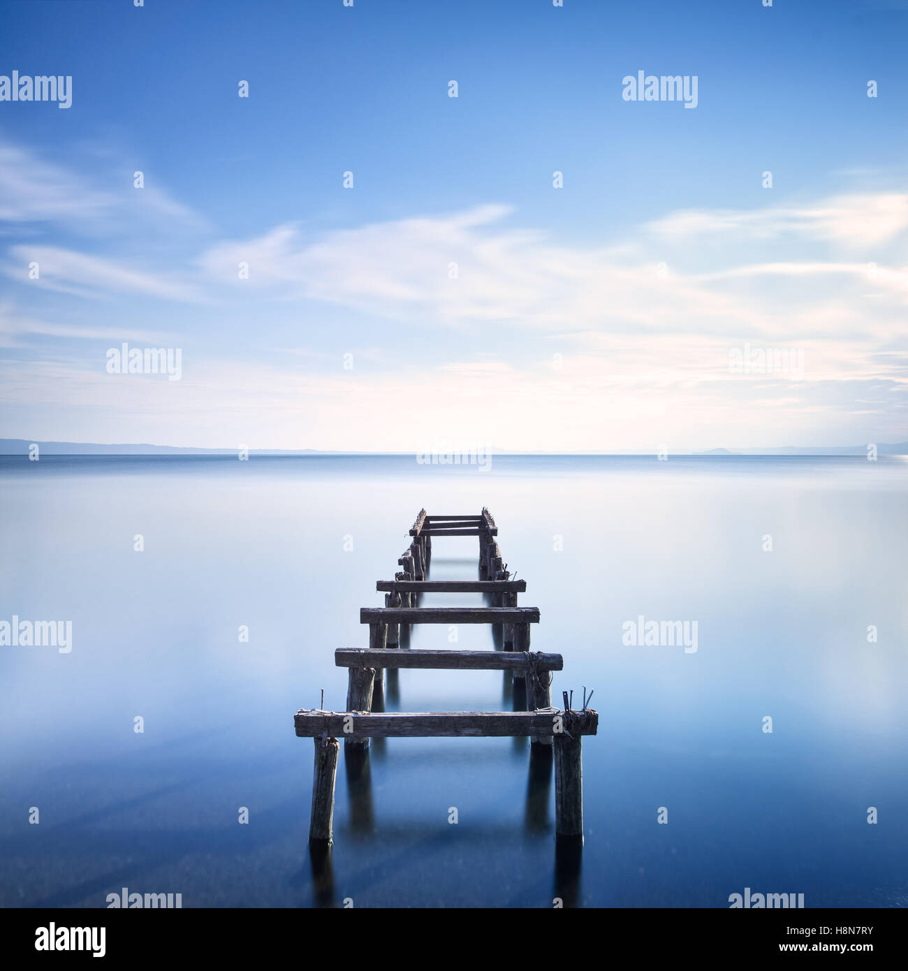 Il molo di legno o molo rimane su un lago blu del tramonto. Fotografie con lunghi tempi di esposizione Foto Stock