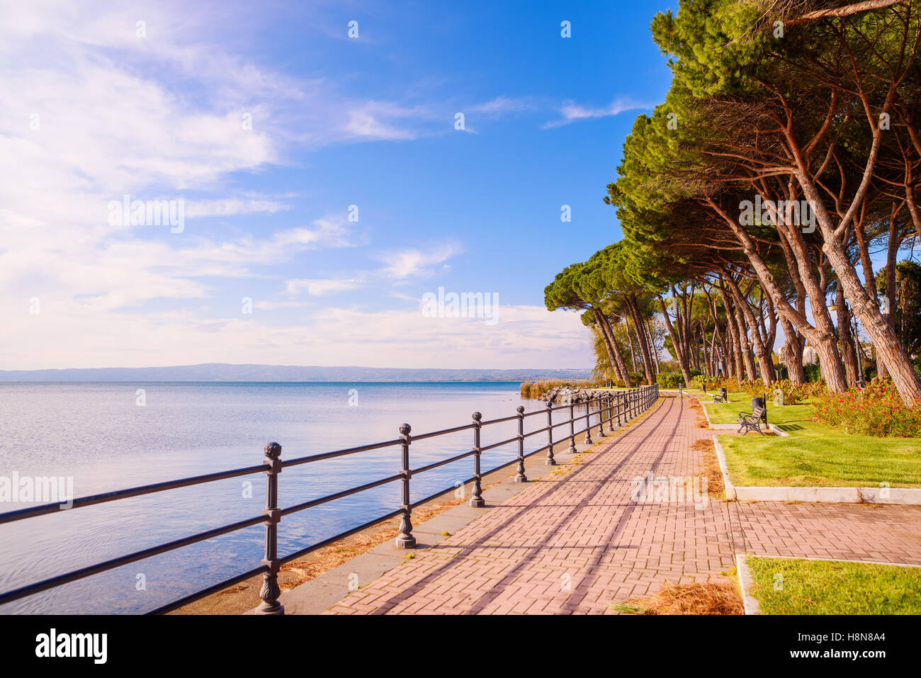 Promenade o esplanade e pini nel lago di Bolsena, Italia. Foto Stock