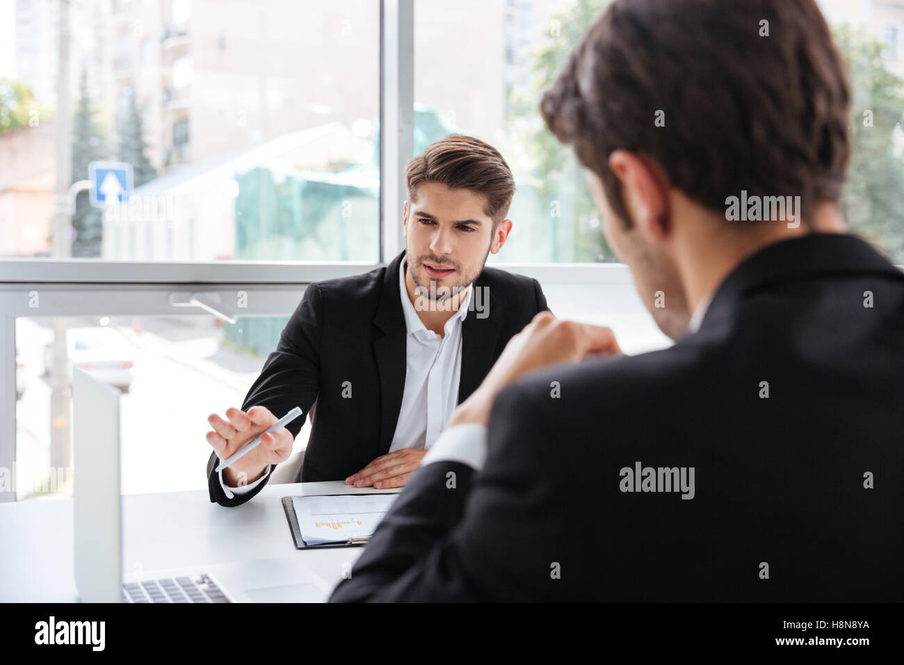 Due concentrati i giovani imprenditori a lavorare con il computer portatile in ufficio Foto Stock