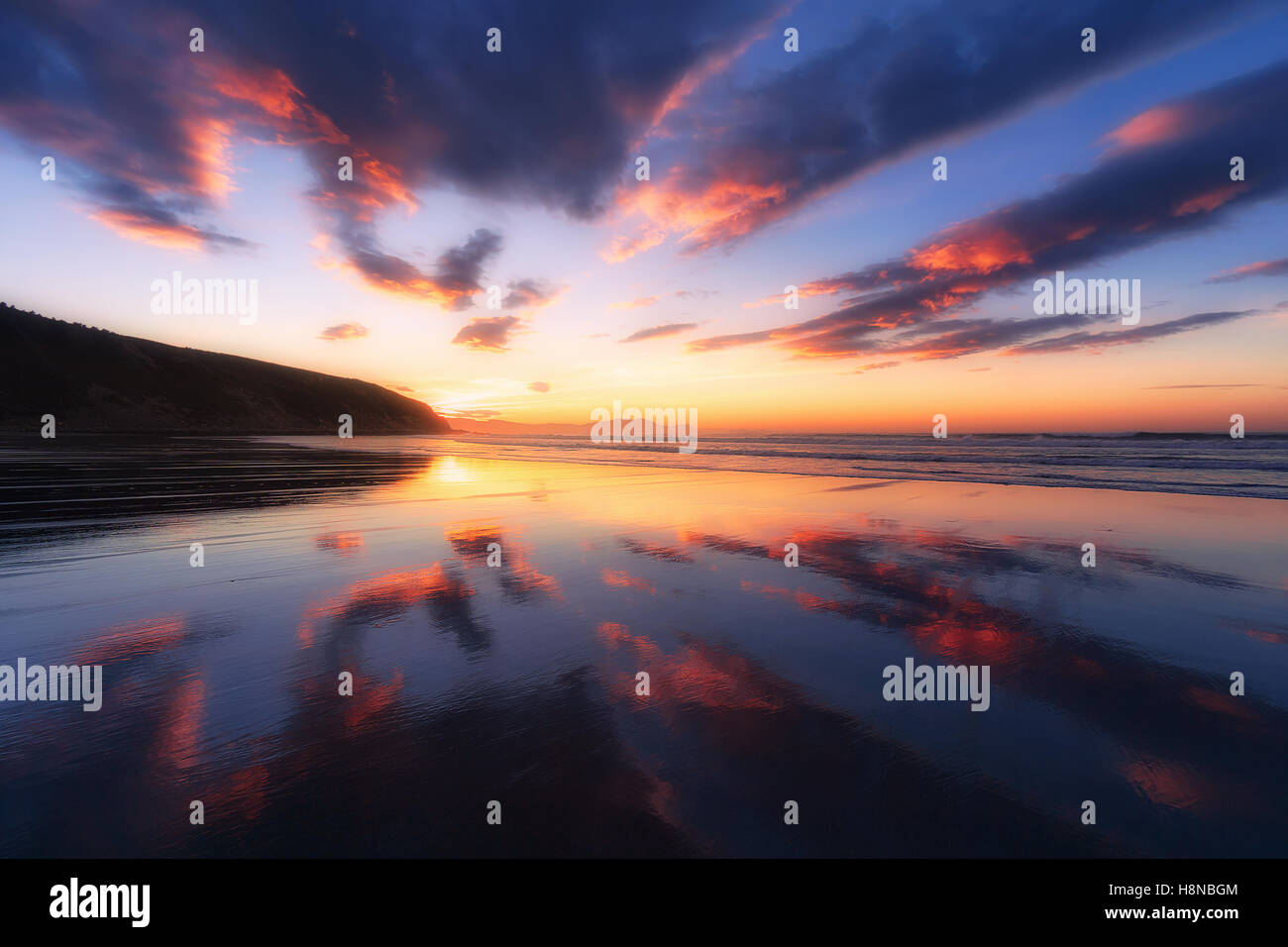 Spiaggia Barinatxe con cloud riflessioni al tramonto Foto Stock