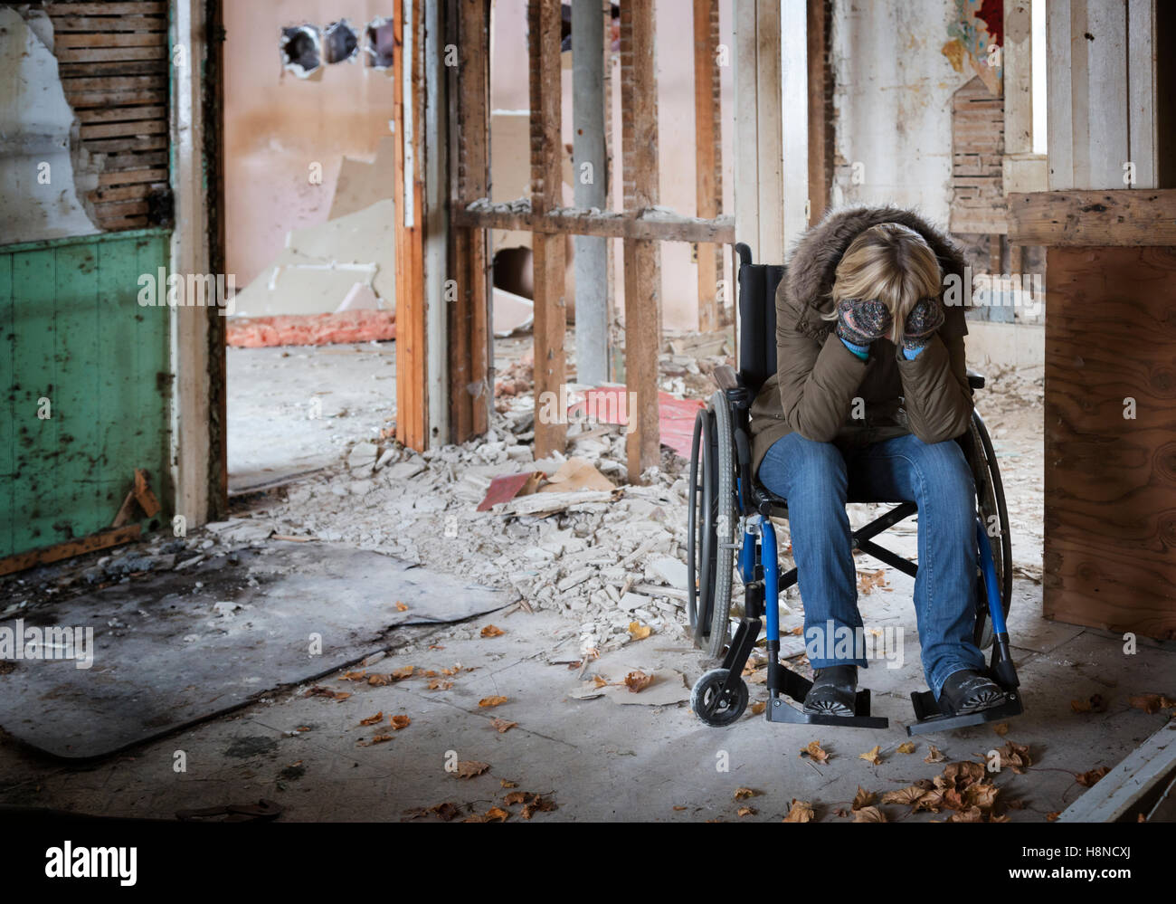 Giovane donna in sedia a rotelle in casa danneggiata Foto Stock