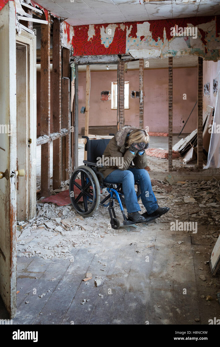 Giovane donna in sedia a rotelle in casa danneggiata Foto Stock