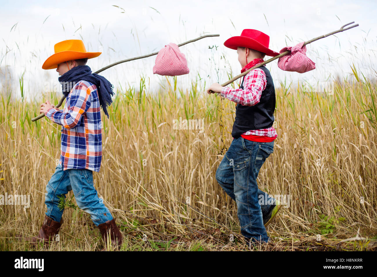 Per i ragazzi (8-9) vestito come cowboy camminando nel campo Foto Stock