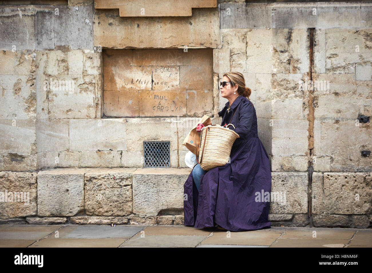 Una donna seduta su una panchina di pietra su una strada di Oxford Foto Stock