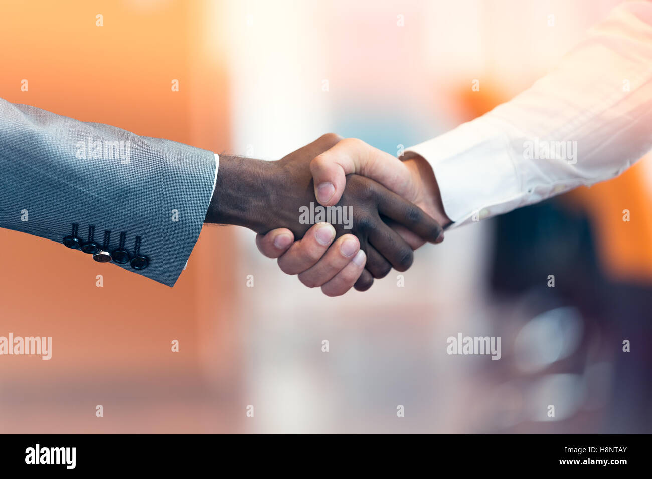 Stretta di mano tra africani e di un uomo caucasico Foto Stock