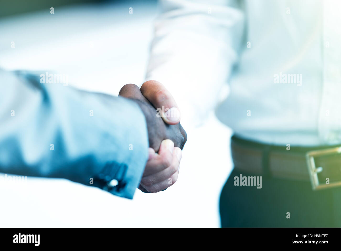 Stretta di mano tra africani e di un uomo caucasico Foto Stock