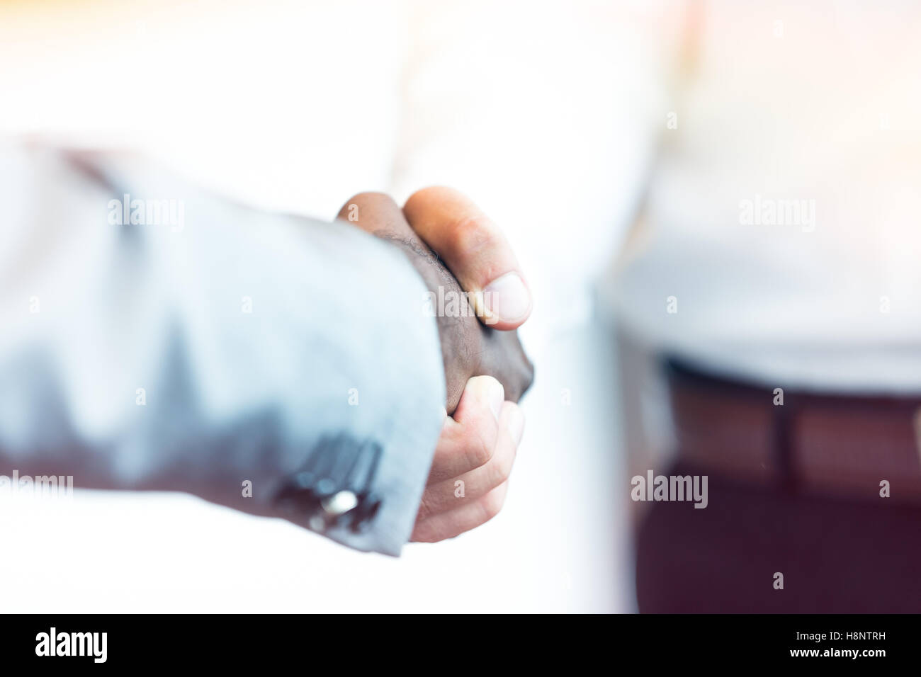 Stretta di mano tra africani e di un uomo caucasico Foto Stock
