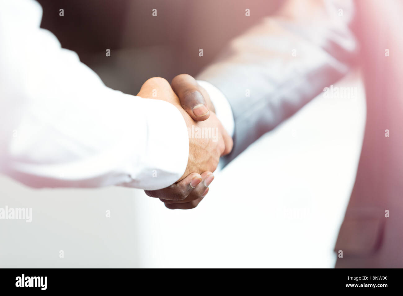 Stretta di mano tra africani e di un uomo caucasico Foto Stock