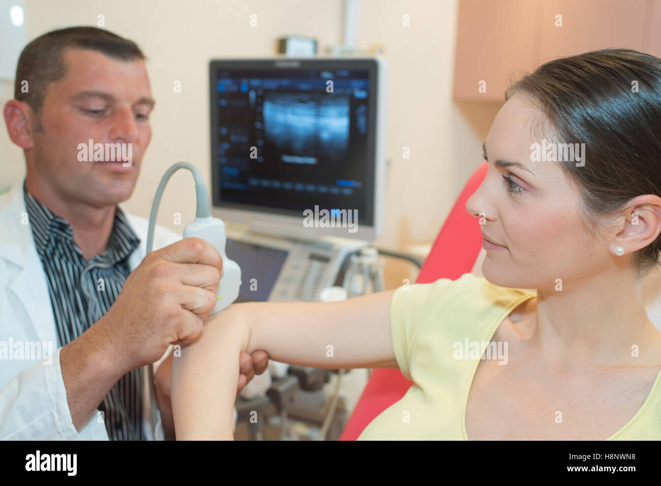Medico maschio rendendo indagine ad ultrasuoni in clinica medica Foto Stock