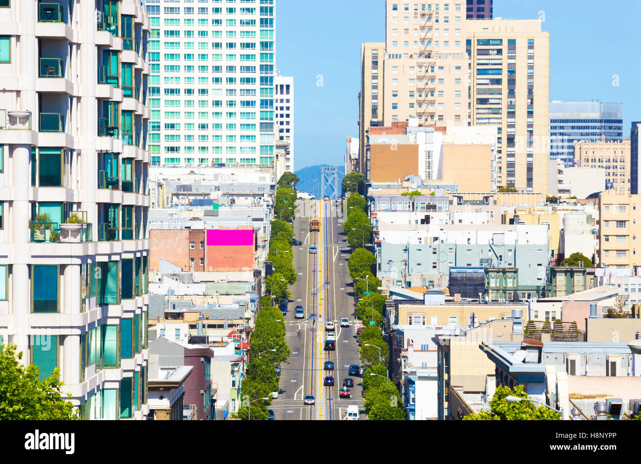 Teleobiettivo distanti visualizza in basso California Street iconica funivia e punta del Bay Bridge tra appartamento residenziale edifici su Foto Stock
