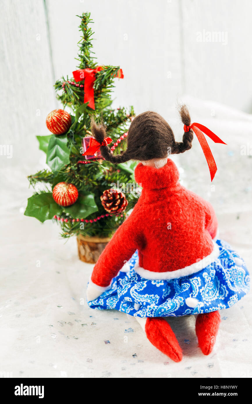 Soffice bambola tessile vicino a un albero di Natale con doni. Foto Stock