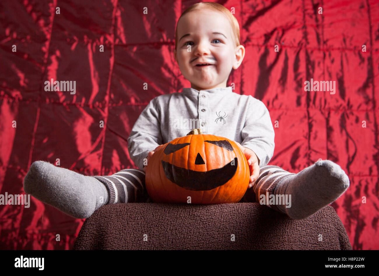 Sorridente little boy dress up per la festa di Halloween. Raso rosso sfondo Foto Stock