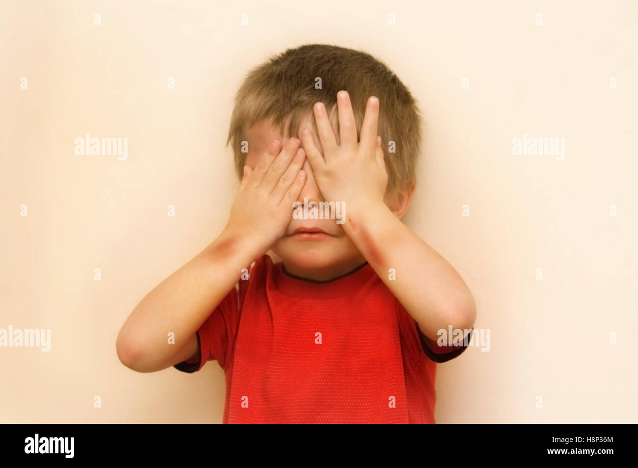 Una immagine concettuale di un abusato bambino nasconde la sua faccia. migliorate digitalmente. Foto Stock