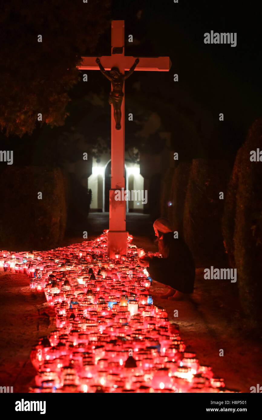 Una vista notturna di una donna tenendo un lampion davanti alla croce al cimitero di Velika Gorica, Croazia. Foto Stock