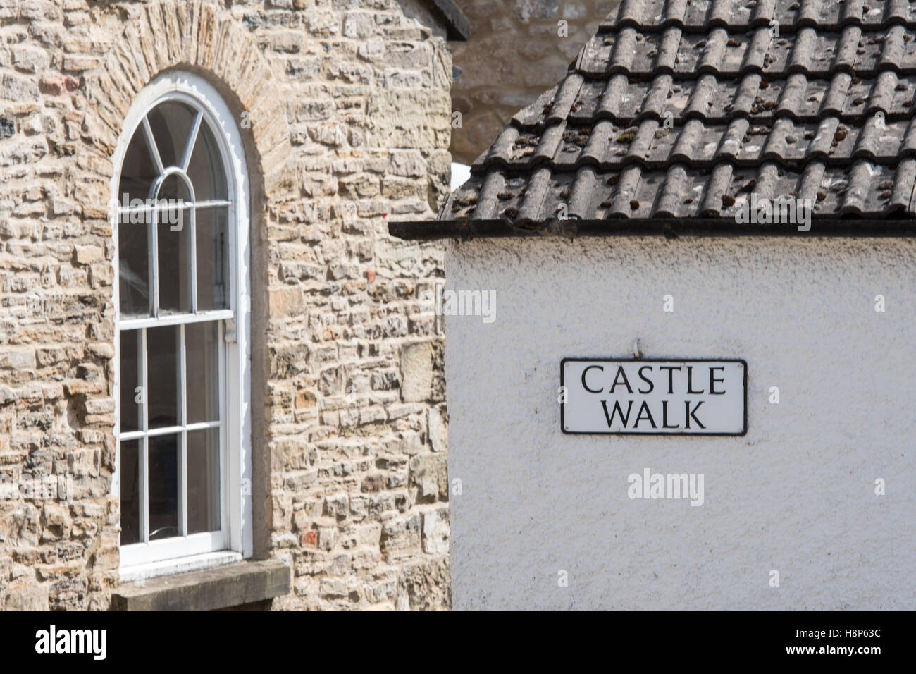 Regno Unito, Inghilterra, Yorkshire, Richmond - Dettaglio di una vecchia finestra di pietra su un edificio e un segno per il castello a piedi nella città di Richmon Foto Stock