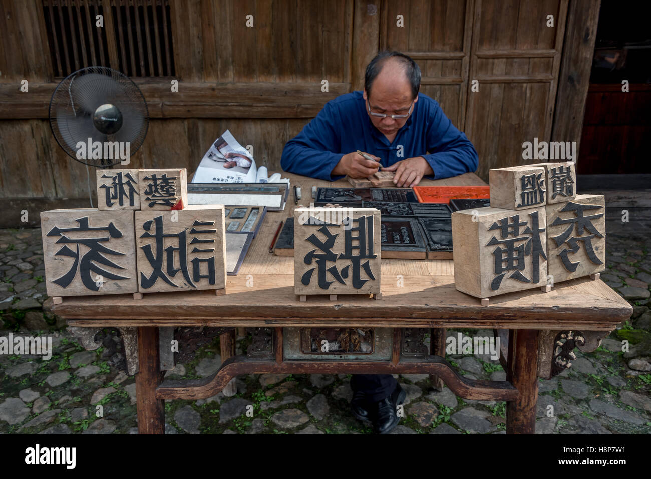 Un maestro addestrato nell'arte cinese di tipo mobile scolpisce la stampa di caratteri in legno a Dongyuan village, Ruian, Cina. Foto Stock