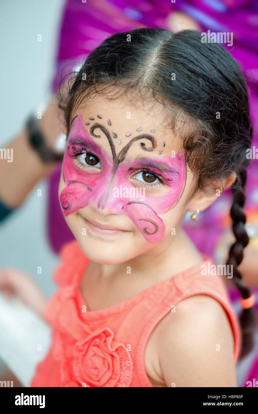 Ritratto di un quattro anni piuttosto carina ragazza giovane bambino con la sua faccia dipinta per il divertimento di una festa di compleanno Foto Stock