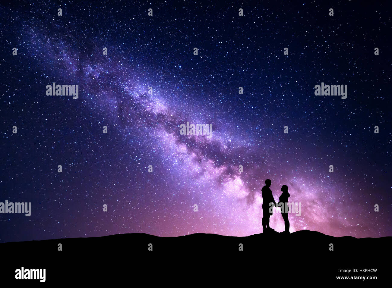 La Via Lattea con silhouette di persone. Paesaggio con cielo notturno con stelle e in piedi un uomo e una donna tenendo le mani sul mountai Foto Stock