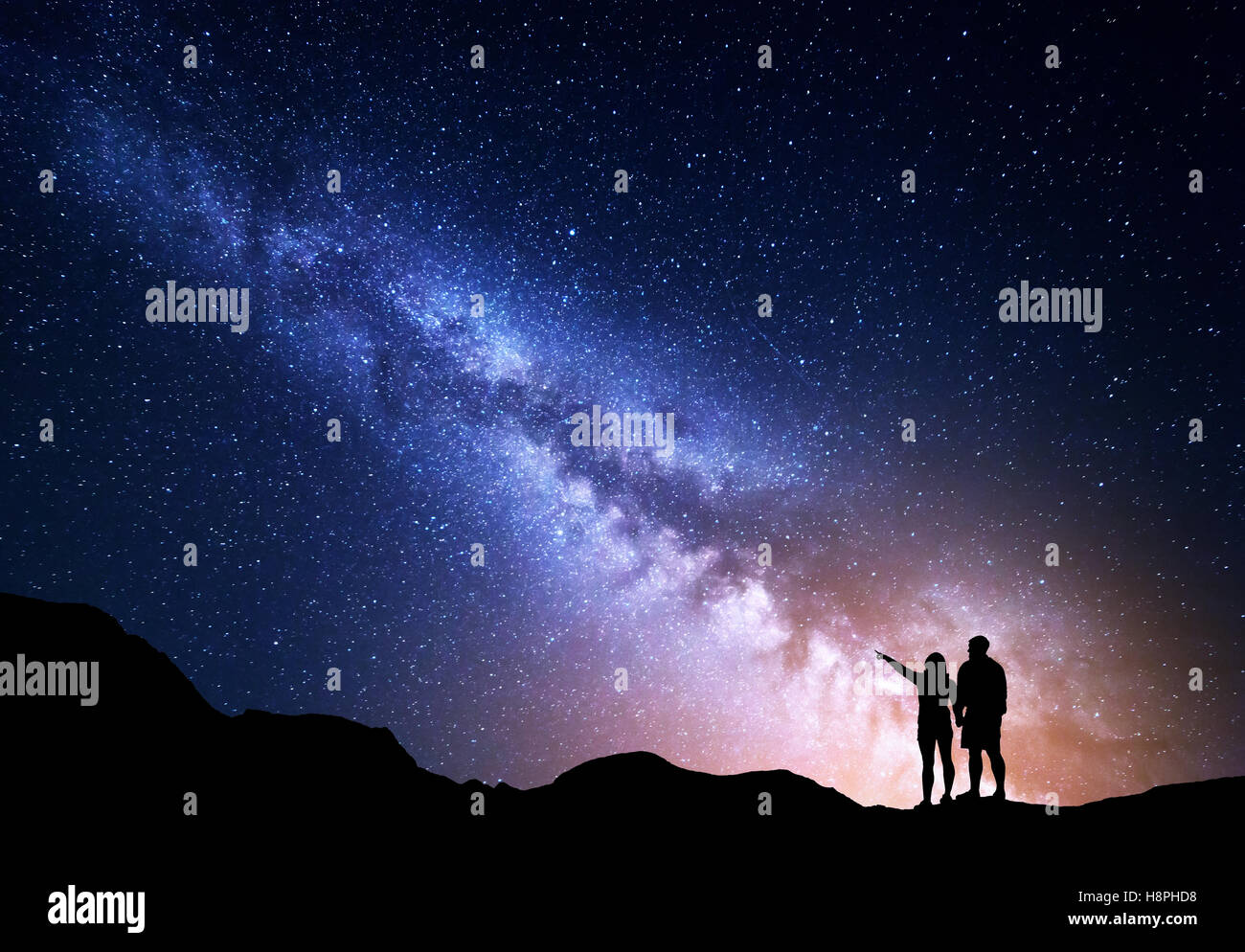 La Via Lattea con persone sulla montagna. Paesaggio con cielo notturno con stelle e silhouette di felice permanente di un uomo e di una donna Foto Stock