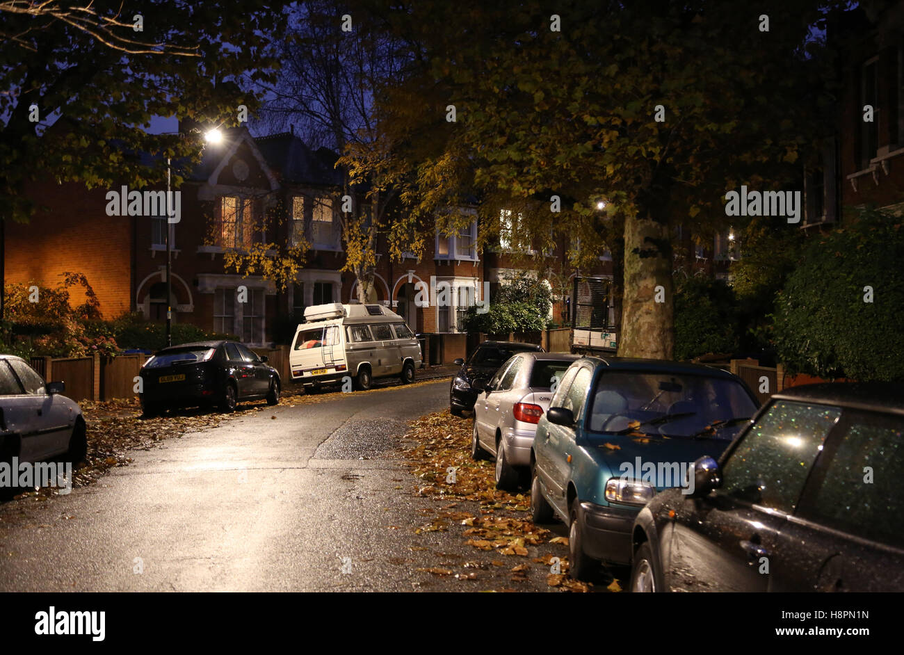 Foglie di autunno coprire i marciapiedi e le strade in un tipico South London street dopo il tramonto su una notte ad umido Foto Stock