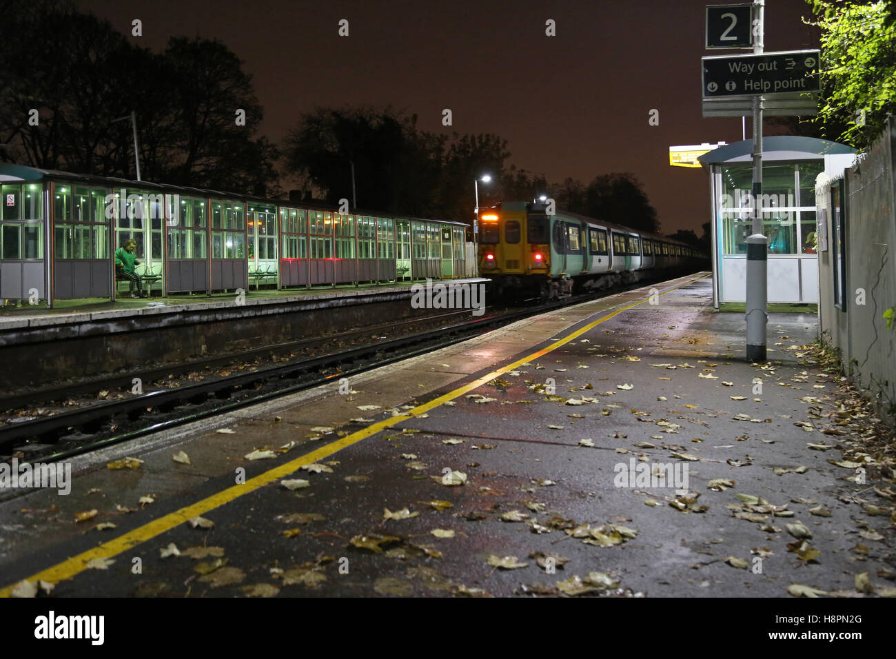 Foglie di autunno in pista e la piattaforma a sud alla stazione ferroviaria di Londra. Un treno lascia la piattaforma per il London Bridge Foto Stock