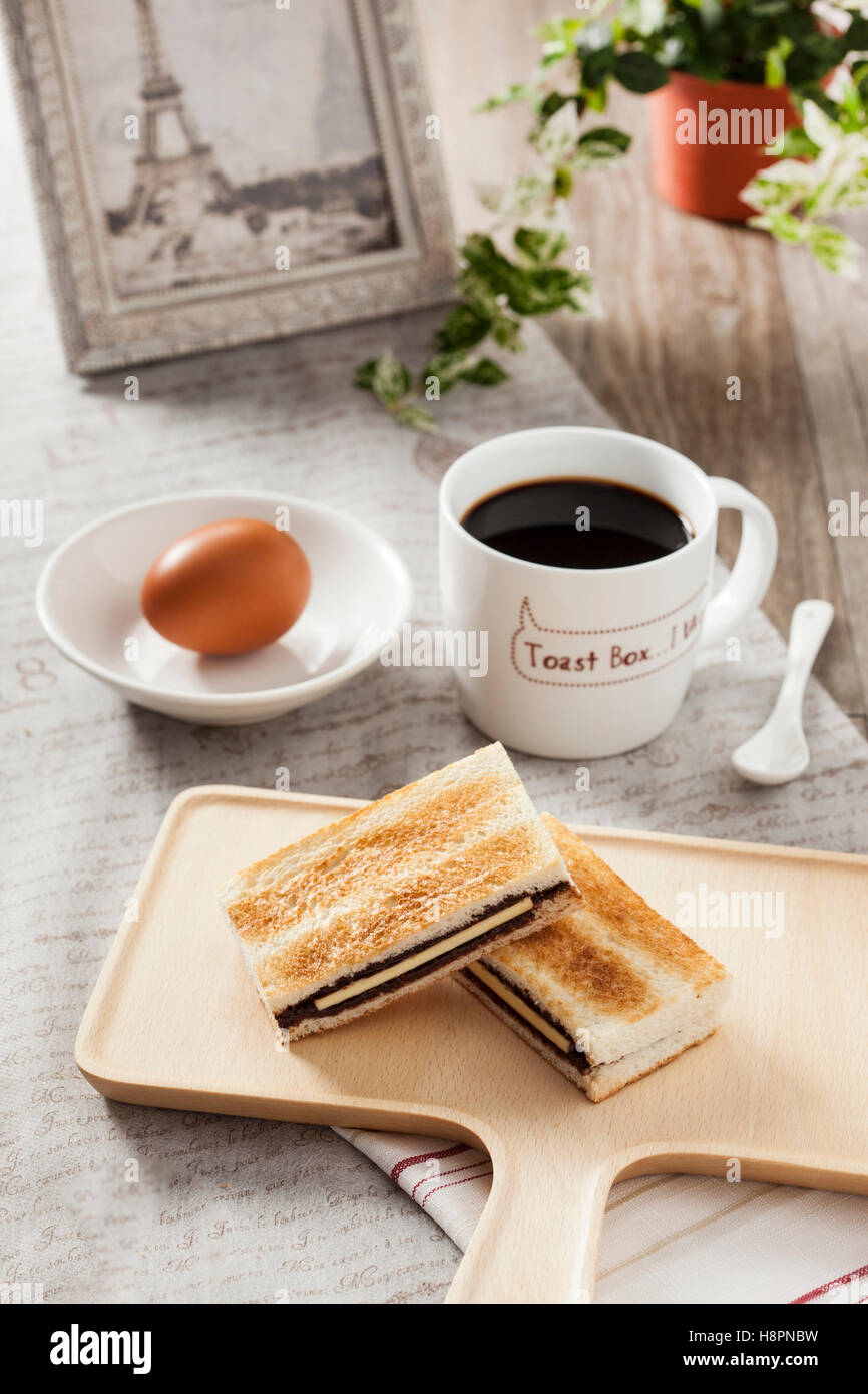 La deliziosa prima colazione con pane tostato, uova e caffè nero su un listone Foto Stock