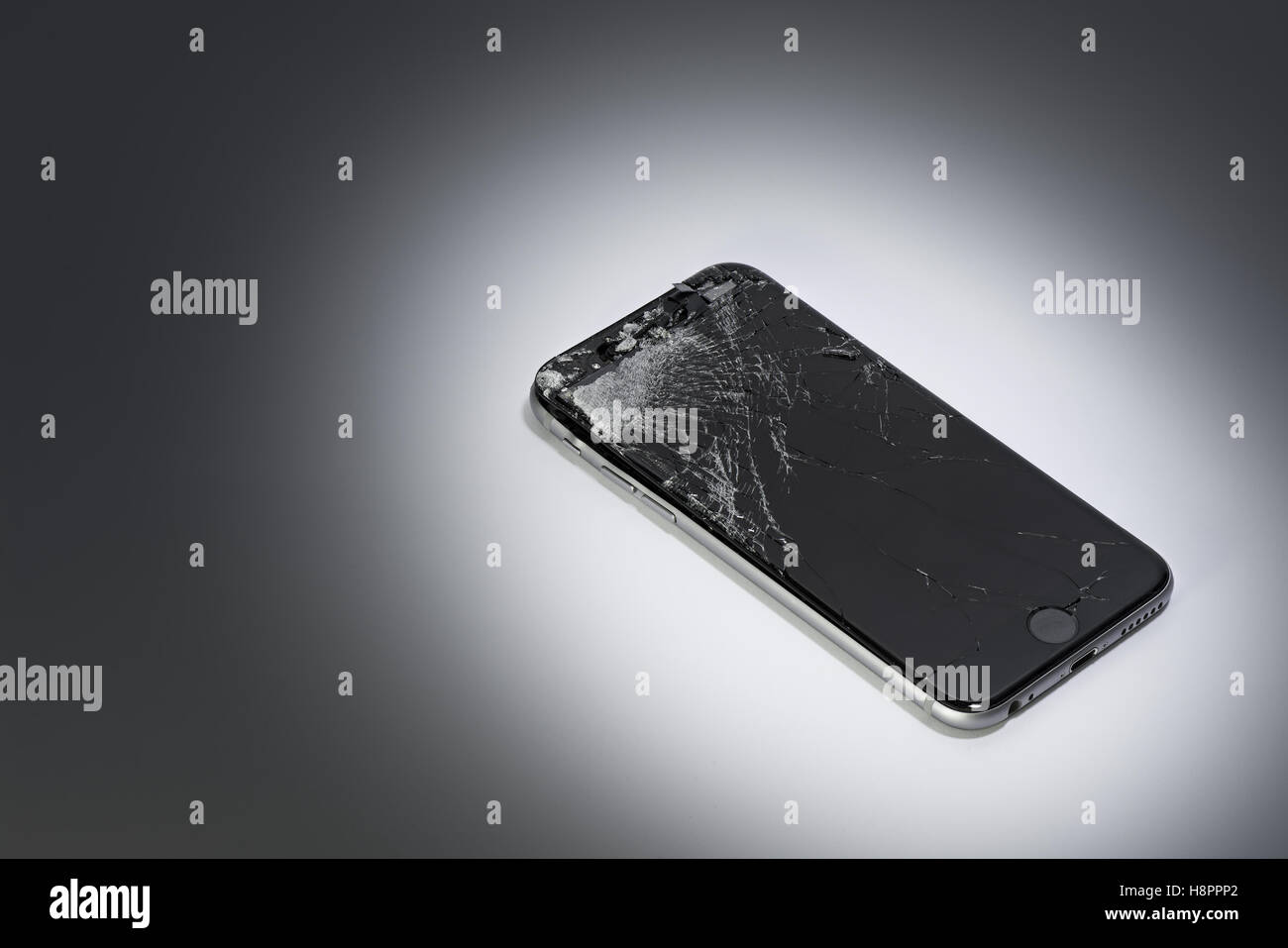 Un telefono cellulare con schermo rotto su un gradiente dello sfondo Foto Stock