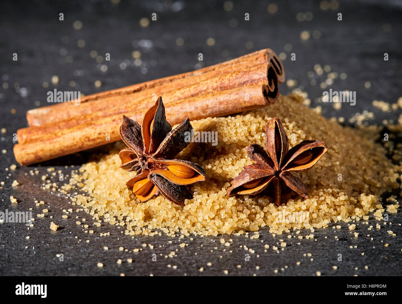 Cumulo di zucchero di canna, bastoncini di cannella e anice stellato sul tavolo di pietra Foto Stock