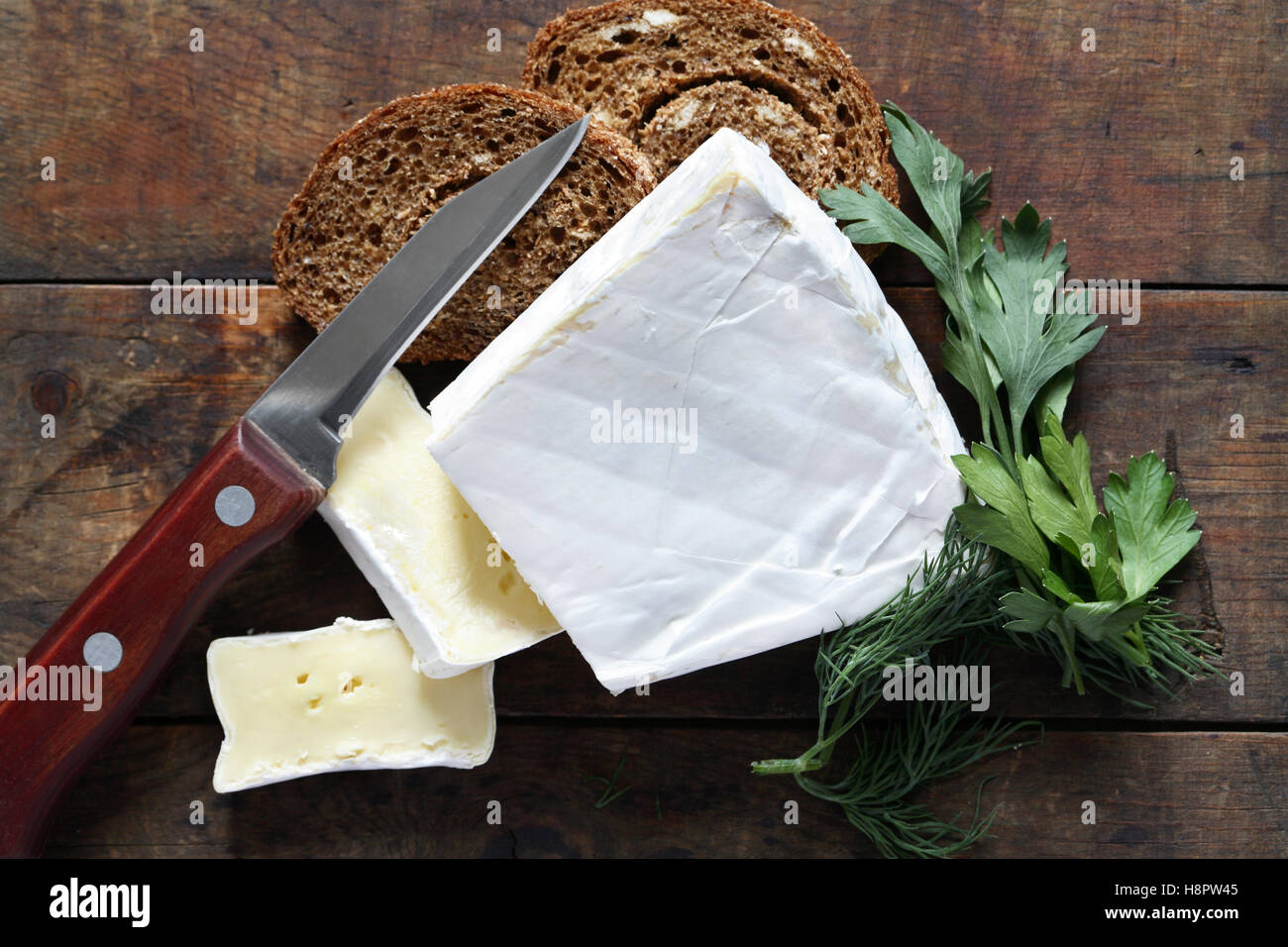 Pezzo di francese Formaggio Brie vicino a coltello e il pane sulla vecchia sullo sfondo di legno Foto Stock