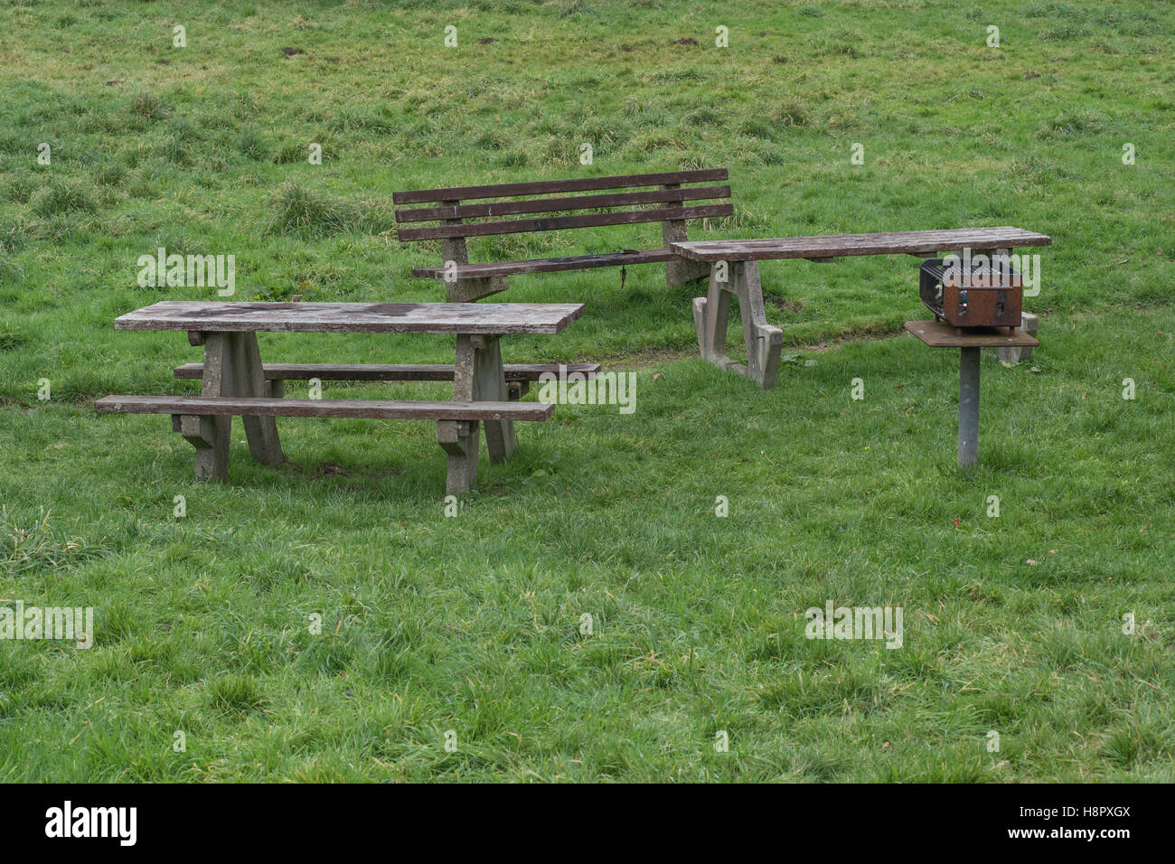 Tavolo da picnic, banchi / sedili unici fissi e barbecue nel parco pubblico area. Foto Stock