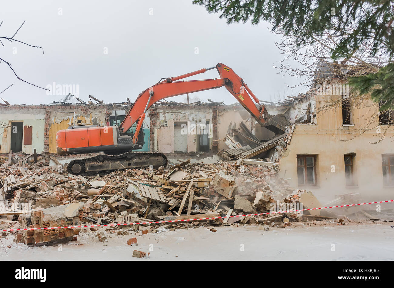 Demolizione di una casa con un escavatore arancione Foto Stock