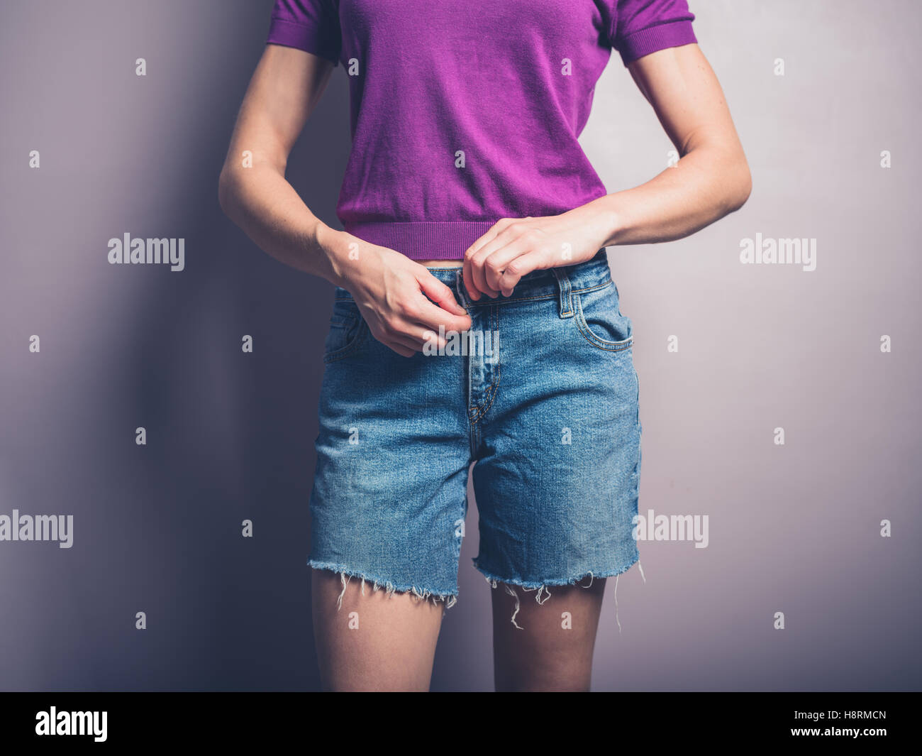 Una giovane donna è la chiusura della cerniera lampo sul suo pantaloncini denim Foto Stock