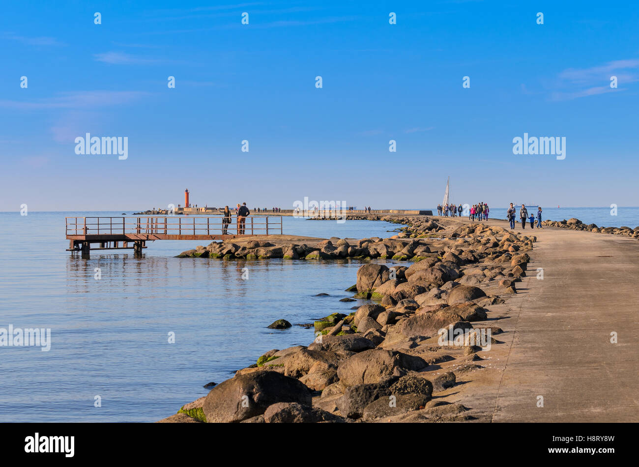 La gente a piedi sul lungomare a Mangalsala e visita red faro, situato a Riga porta a mare, Latva Foto Stock