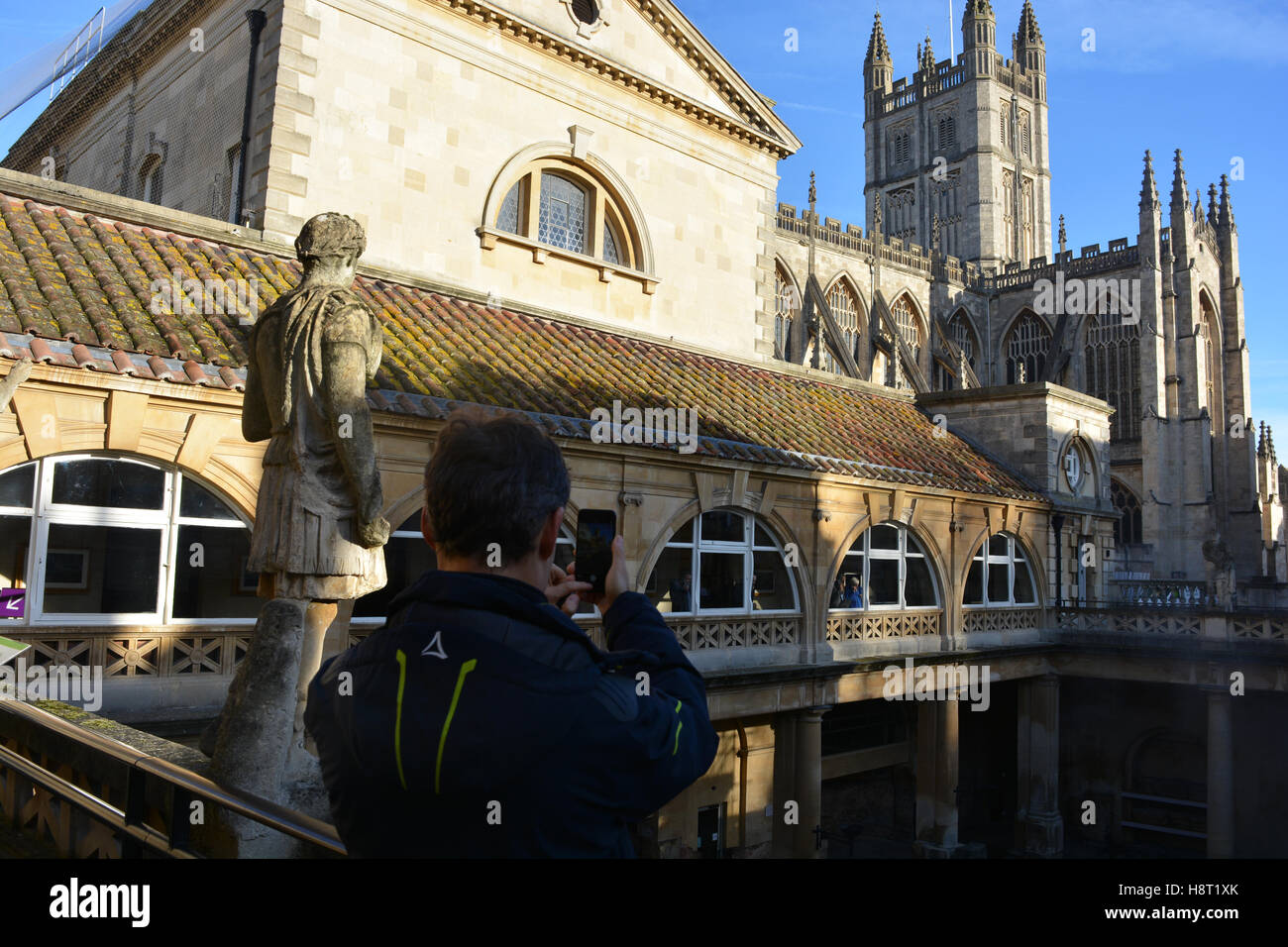 Uomo di scattare le foto su un telefono di bagni romani, con l'Abbazia di Bath in background, bagno, Somerset, Inghilterra Foto Stock