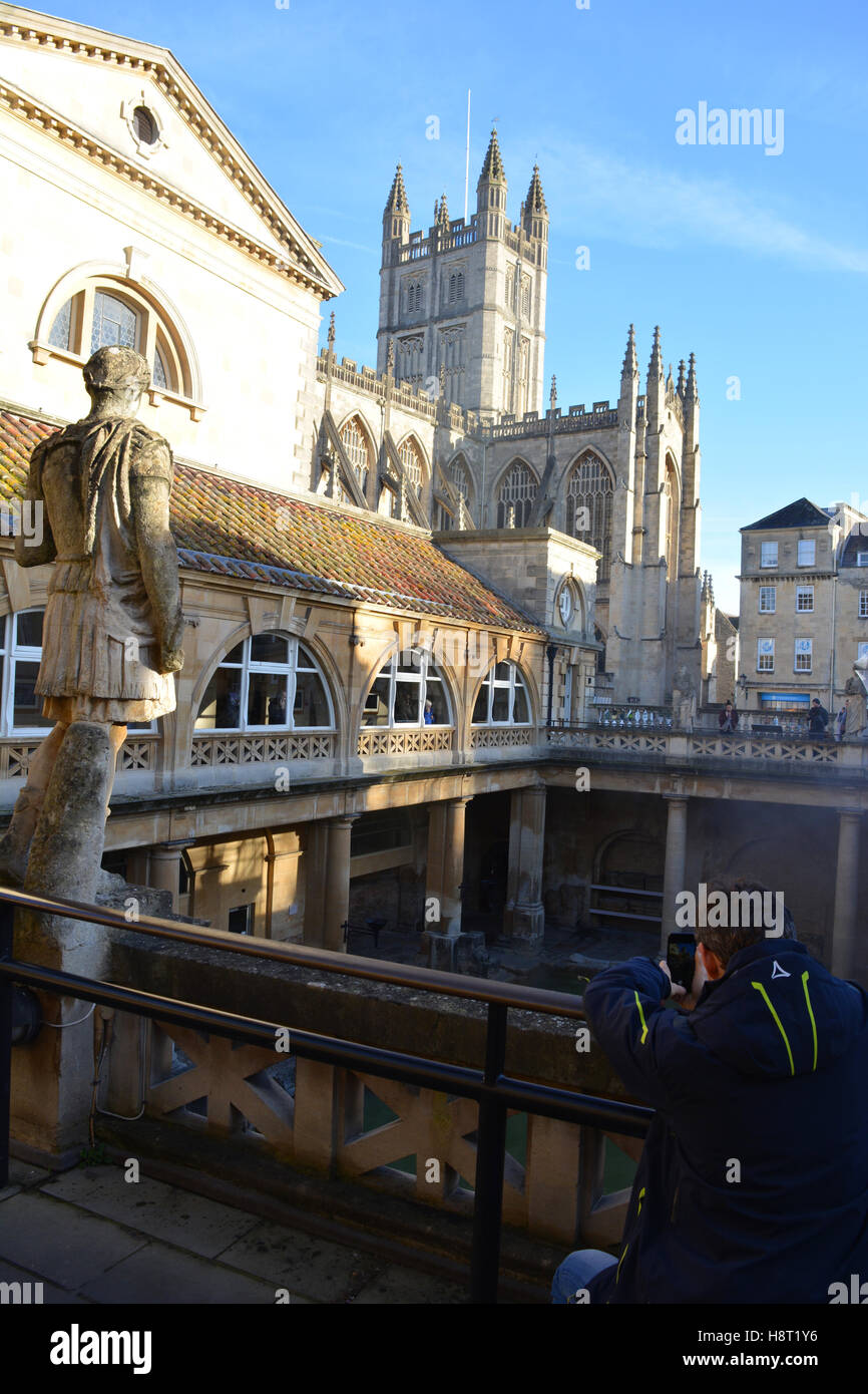 Uomo di scattare le foto su un telefono di bagni romani, con l'Abbazia di Bath in background, bagno, Somerset, Inghilterra Foto Stock