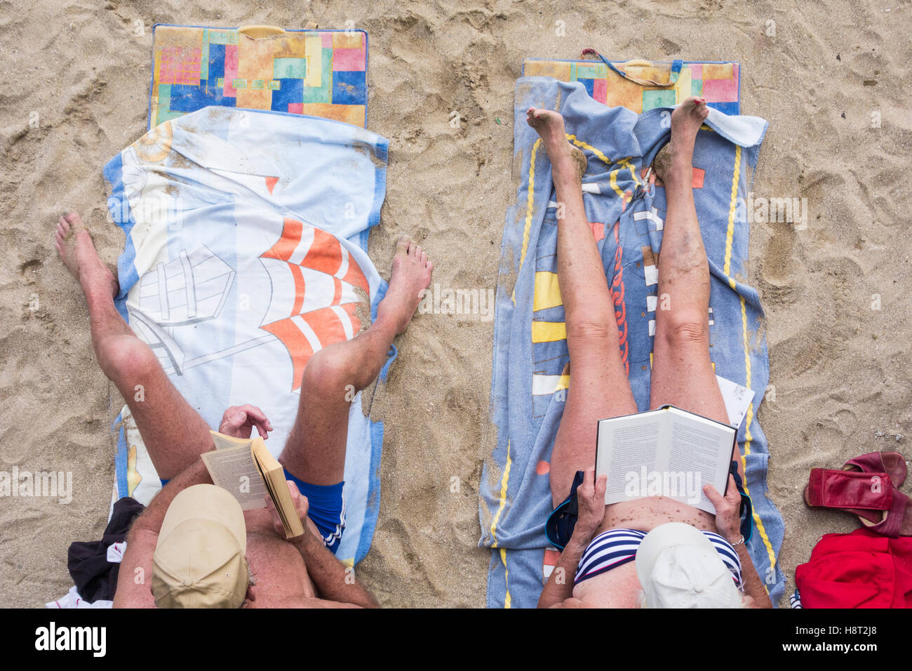 Coppia matura lettura sulla spiaggia. Foto Stock