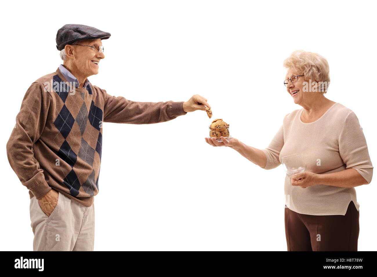 Uomo maturo prendendo un cookie da una donna matura con un vaso isolato su sfondo bianco Foto Stock