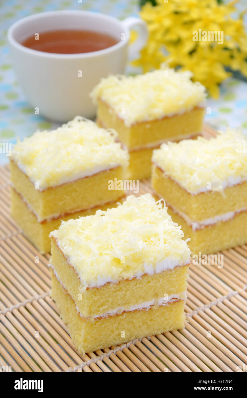 La torta in due strati con il formaggio come un toping, con una tazza di tè caldo come sfondo Foto Stock