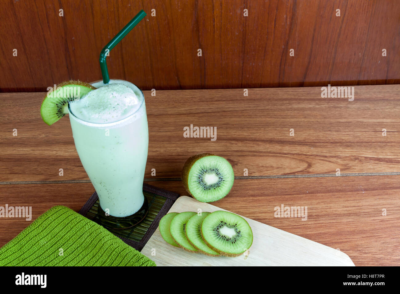 Un sano frullato verde realizzato da kiwi verde con cannucce su un tavolo di legno. Foto Stock