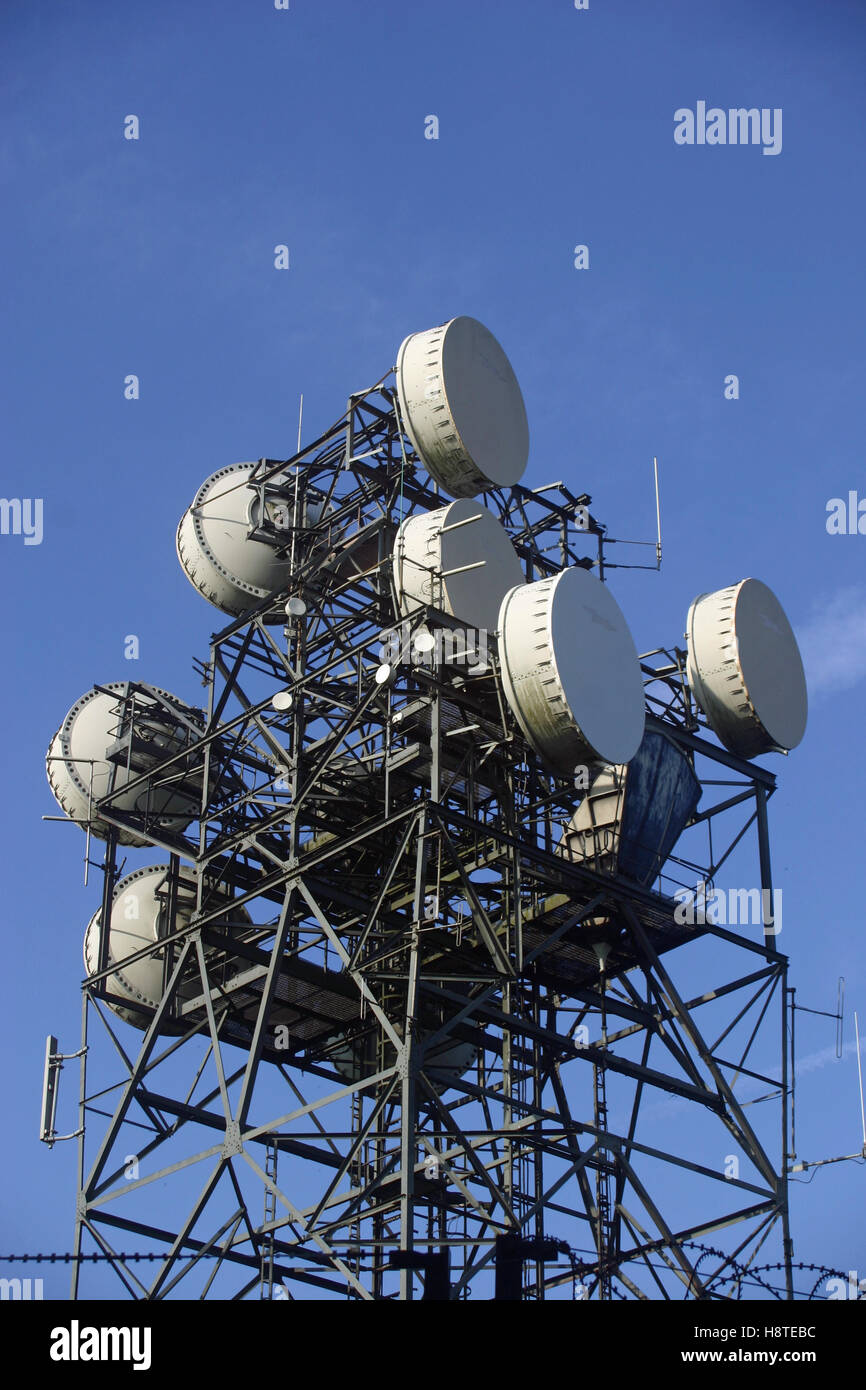 Metallo montante di telecomunicazioni con antenne e piatti. Sullo sfondo di un cielo blu con bianco contrails di aeromobili. Foto Stock