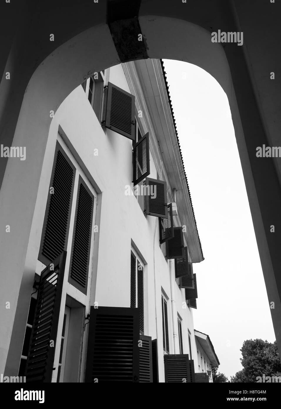 Fila di finestre al piano superiore dell'edificio vista dall'esterno al piano terra attraverso un cancello. La fotografia in bianco e nero. Foto Stock
