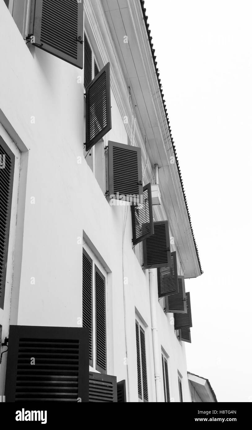 Fila di finestre al piano superiore dell'edificio vista dall'esterno al piano terra. La fotografia in bianco e nero. Foto Stock