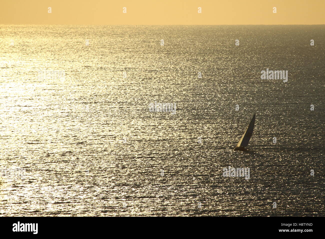 Un tramonto d'oro tende a lone yacht come vele al largo della costa di Scarborough in NSW, Australia. Foto Stock